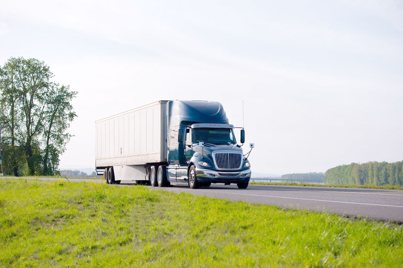 Một chiếc xe đầu kéo màu trắng đang kéo container trên đường